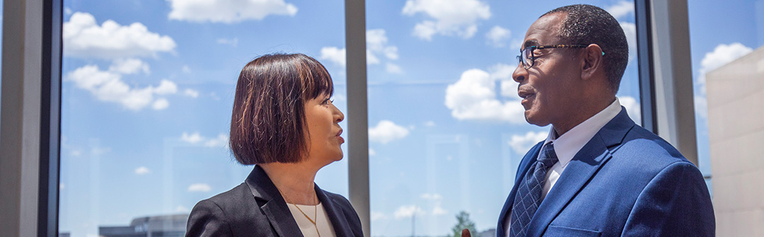 A business man and woman talking in front of a window